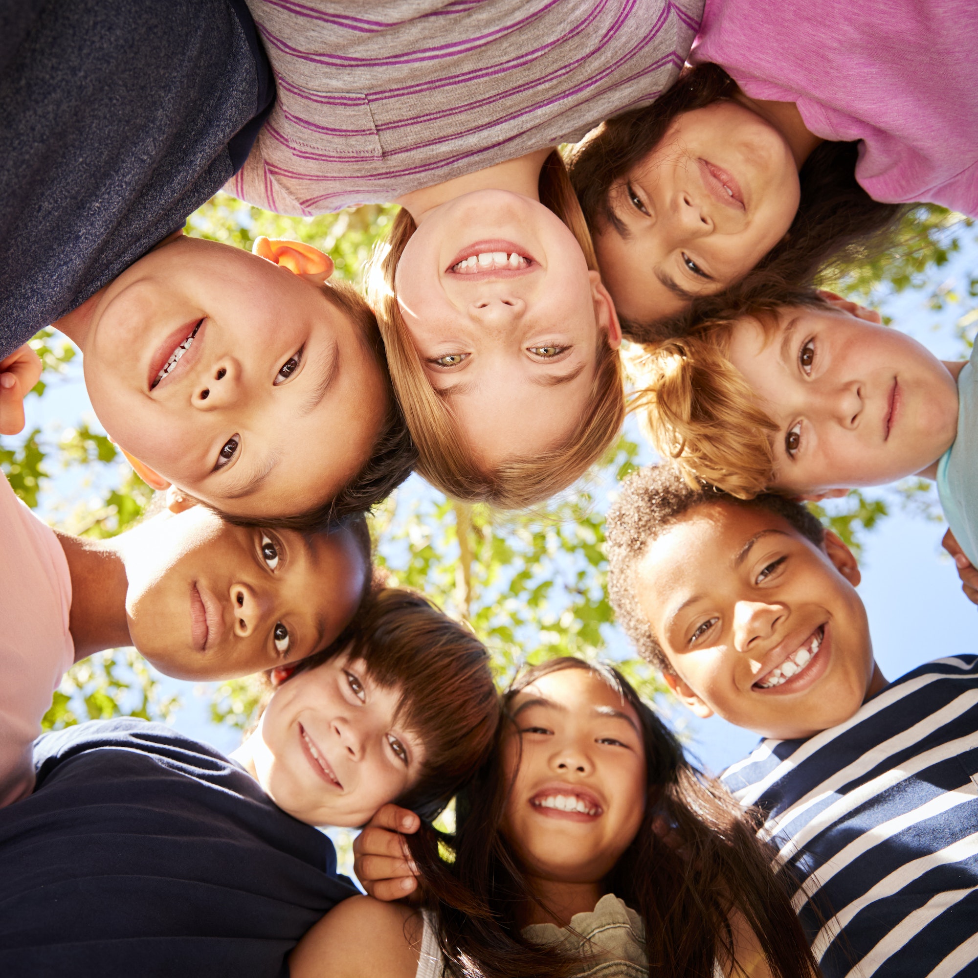 Group of kids outdoors looking down at camera, square format